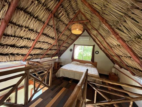 a bedroom in a thatch roofed room with a bed at Embajada Universal By La Eufemia Group in Huay Pix