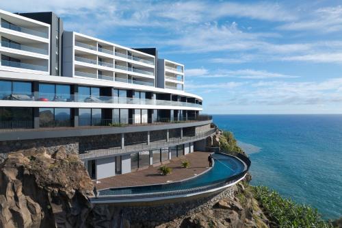 a building on a cliff next to the ocean at Atlantic Heights Varandas do Atlântico by Holiday Rental Madeira in Câmara de Lobos