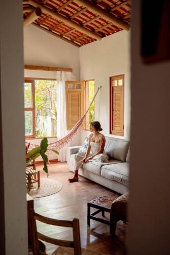 a woman sitting on a couch in a living room at Casa Teçá in Guriú
