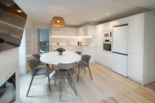 a white kitchen with a white table and chairs at Earra - Goxo - centro, 450m playa in Zarautz