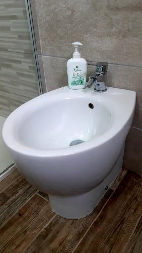 a white bathroom sink with a bottle of soap on it at P I G Ó 's HOUSE in Budoni