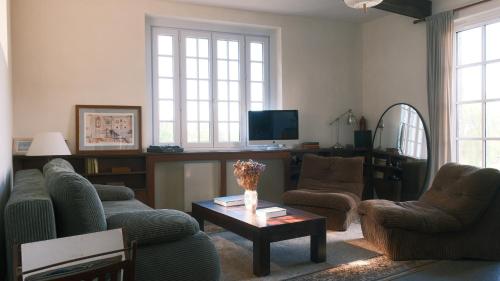 ein Wohnzimmer mit zwei Sofas und einem Tisch in der Unterkunft Maison Maa, Maison de gardien, à 10 min à pieds de St Valery sur somme le long du canal in Boismont