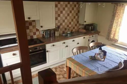 a kitchen with a table and chairs and a kitchen with white cabinets at Seaside Cottage in HAW
