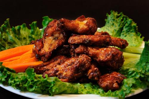 a plate of food with chicken wings and carrots at Lakeview Inns & Suites - Fort Saskatchewan in Fort Saskatchewan