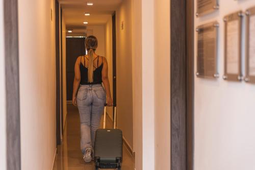 a woman walking down a hallway with a suitcase at Hotel Boutique Business Center in Cali