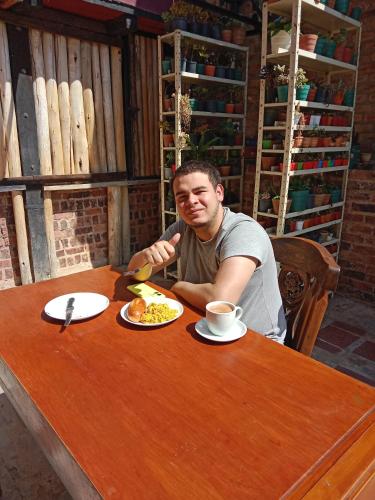 a man sitting at a table with a plate of food at Arte sin Fronteras Hostel in Paipa
