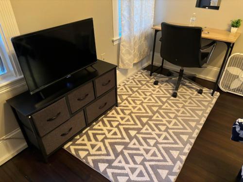 a living room with a tv and a desk and two chairs at HomeStay in Boston - Dorchester Fields Corner Area in Boston