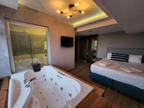 Un baño con bañera y una cama. en Martin City Hotel, en Bursa