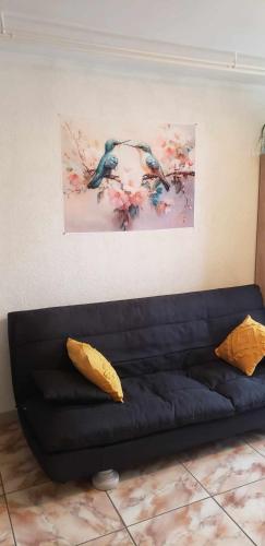a black couch in a living room with a painting on the wall at Au Coeur du Jura, Logement au calme in Champagnole