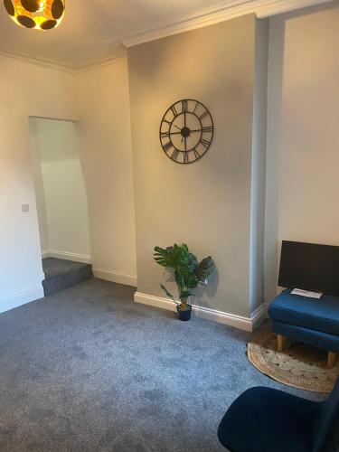 a room with a clock on the wall and a plant at Happy Homes in Stoke on Trent