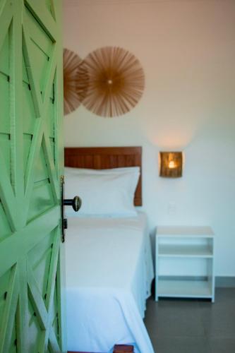 a bedroom with a bed and an open door at Pousada Fenícia in Japaratinga