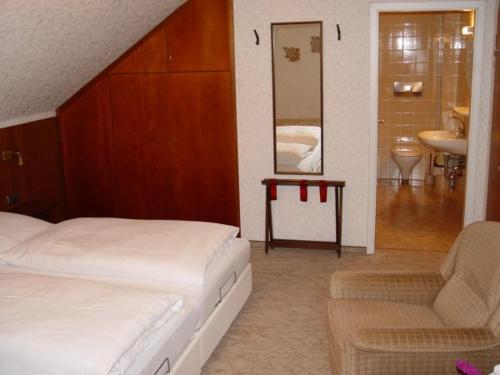 a bedroom with a bed and a chair and a mirror at Café Pension Sonnenkanzel in Staatsbad Brückenau