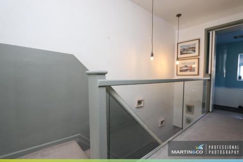 a staircase in a building with a glass railing at The PINK House , FREE Parking , 3 Bedrooms , Garden , close to M4 and countryside! in Rogerstone