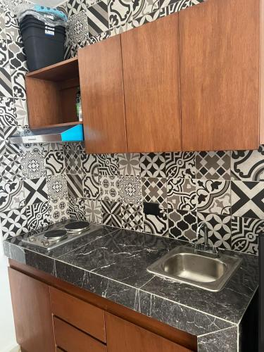 a kitchen with a sink and a tile wall at Apartamentos Marea CLOSE TO THE AIRPORT in Cancún