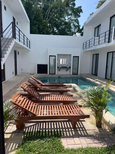 a row of wooden benches next to a swimming pool at Apartamentos Marea CLOSE TO THE AIRPORT in Cancún