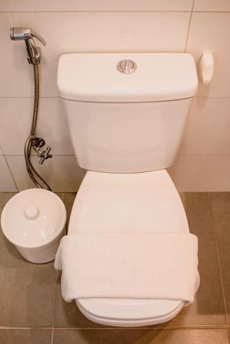 a white toilet in a bathroom with white towels at Pousada Fenícia in Japaratinga