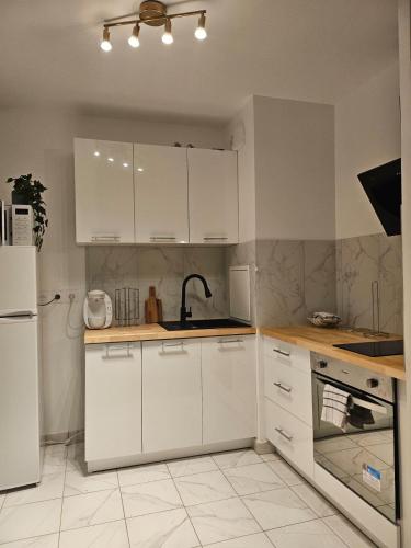 une cuisine avec des armoires blanches, un évier et un réfrigérateur dans l'établissement Appart 10 min Euro Disney - Bussy Saint Georges, à Bussy-Saint-Georges