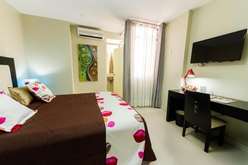 a bedroom with a bed and a desk and a television at El Principe Hoteles in Piura