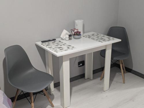 Una mesa blanca con dos sillas al lado de una mesa con una mesa en Компактная студия в центре, en Chişinău