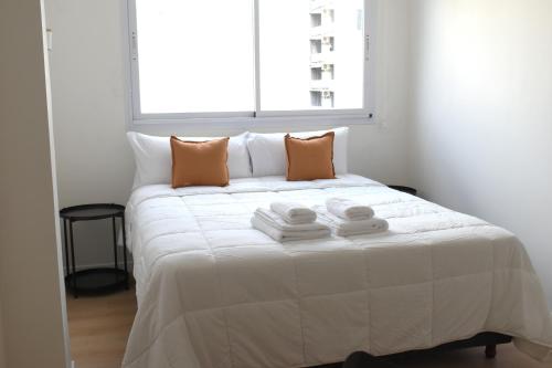 a white bed with towels on it in a room with a window at Torrar Suites in Buenos Aires