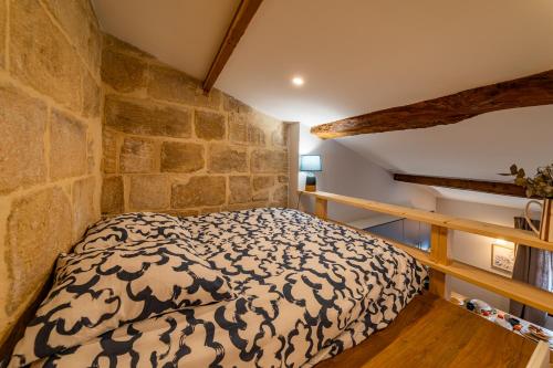 a bed in a room with a stone wall at Duplex Caché Toits & Tradition in Sommières