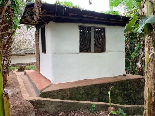 a small white building with a porch and a window at El Zopilote in Balgue