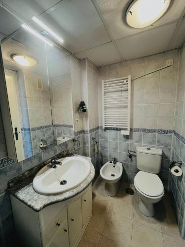 a bathroom with a sink and a toilet and a mirror at Casa Soñada -Appartment with pool and garage in Los Alcázares