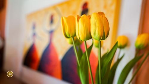 a group of yellow flowers in front of a painting at Villa Gambula - Relax and Pool in Perdaxius