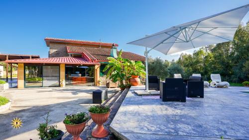 a patio with an umbrella and chairs and a building at Villa Gambula - Relax and Pool in Perdaxius