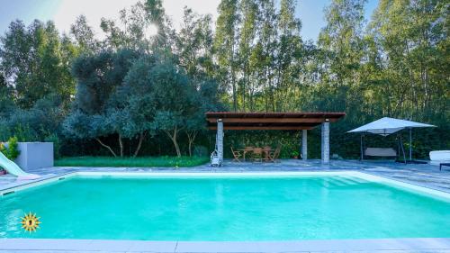 a swimming pool with a pergola and an umbrella at Villa Gambula - Relax and Pool in Perdaxius