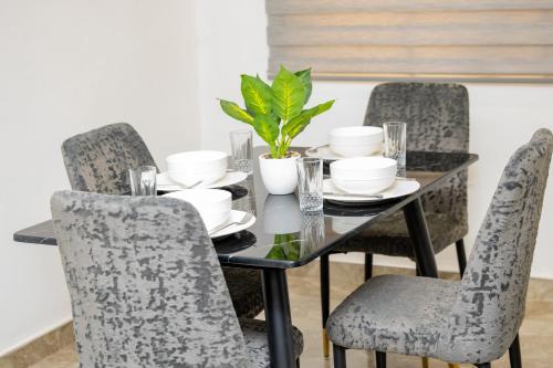 a dining room table and chairs with a glass table and a plant at Luxecom Apartments in Ashalebotwe