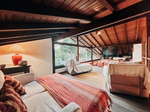 a bedroom with a large bed and a large window at Casa na Serra com 7 Suites em Correas - Petrópolis in Bom Sucesso