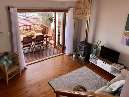 a living room with a couch and a television and a balcony at Cape Town cottage near colony of penguins in Simonʼs Town