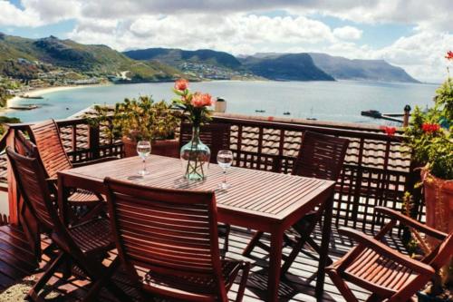 a wooden table with wine glasses and a view of the water at Cape Town cottage near colony of penguins in Simonʼs Town