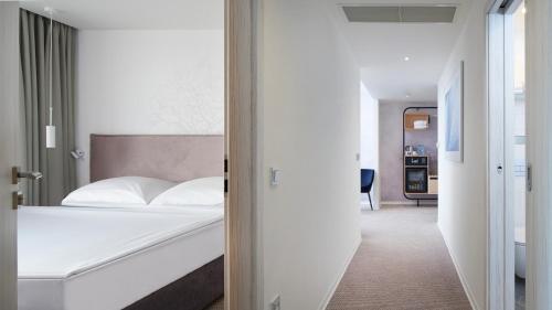 a white bedroom with a bed and a hallway at OREA Resort Santon Brno in Brno