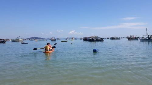 a woman in a kayak in the water with boats at Casa 3 quartos com Piscina no centro de Penha - SC in Penha
