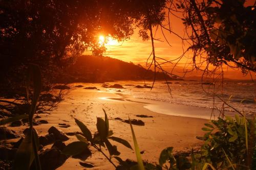 a sunset on a beach with the sun setting at Casa 3 quartos com Piscina no centro de Penha - SC in Penha