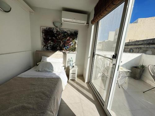 Traditional Maltese Townhouse في سليمة: غرفة نوم بها سرير ونافذة كبيرة