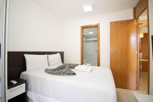 a bedroom with a white bed with a robe on it at OZPED Flats Particulares Edifício Life Resort in Brasilia