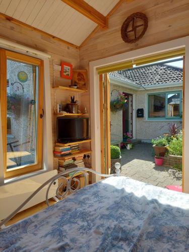a room with a bed and a window and a television at Baxters Bonnie Garden in Passage West