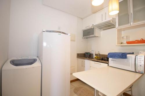 a white refrigerator in a kitchen with a table at OZPED Flats Particulares Edifício Life Resort in Brasilia