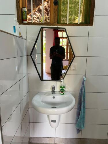 a man taking a picture of a sink in a bathroom at David Crater Homestay in Lushoto