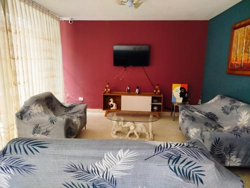a bedroom with a bed and two chairs and a tv at Hotel Los Ebanos in Piura