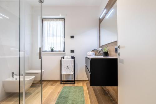 un bagno con lavandino, WC e specchio di ELVY Garda Living Garden a Riva del Garda