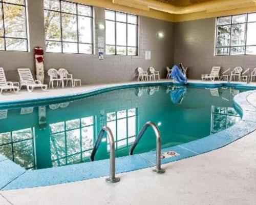 une grande piscine dans un hôtel avec des chaises et des tables dans l'établissement Clarion Inn I-94 near Expo Center, à Kalamazoo