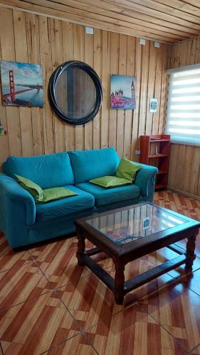 a living room with a blue couch and a coffee table at Espiral Turquesa Cabañas y Departamentos in Melipeuco
