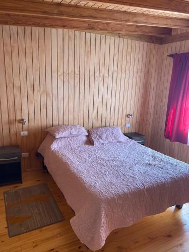 a bedroom with a bed in a wooden wall at Cabaña M&R 2 in Lago Ranco
