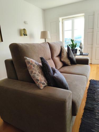 a brown couch with pillows on it in a living room at Alma Da Vila in Ponte de Lima