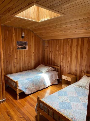 a bedroom with two beds in a room with wooden walls at Hostal de Campo in Ensenada