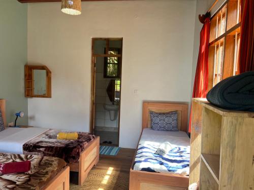 a room with two beds and a bathroom with a mirror at David Crater Homestay in Lushoto